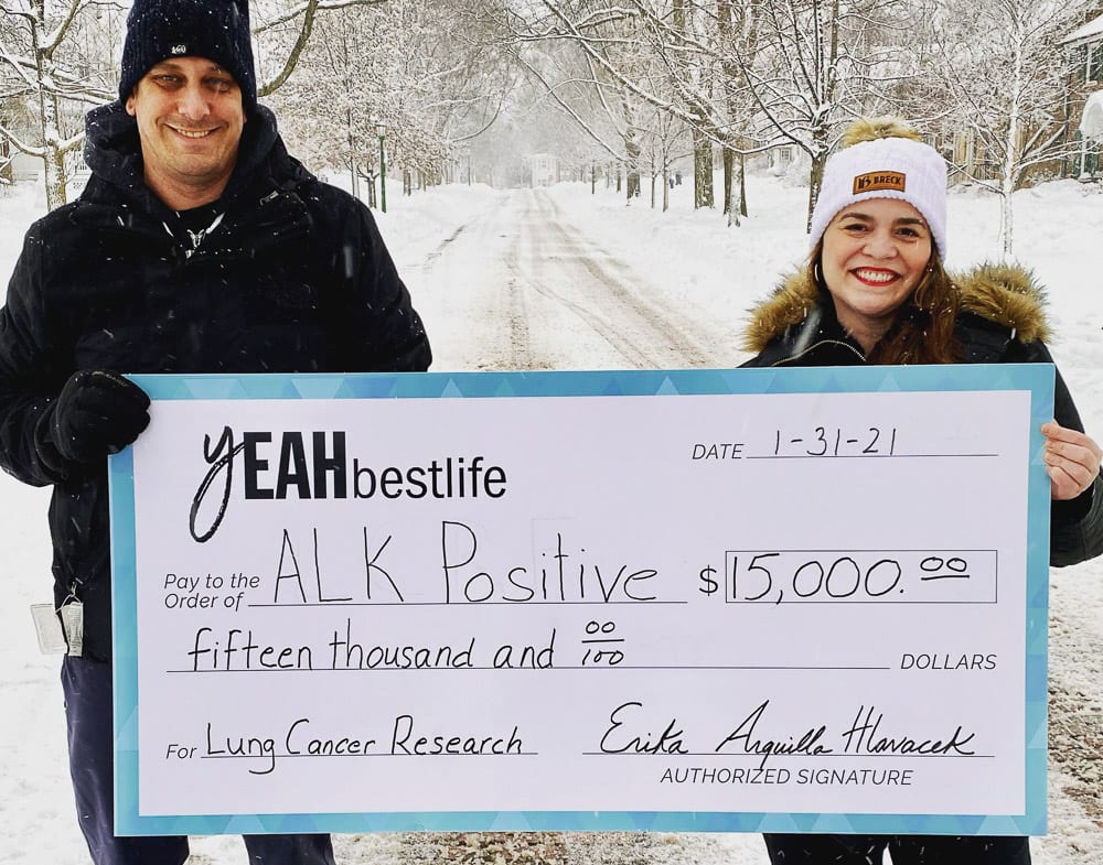 Erika and Jeff Hlavacek holding giant check for $15,000 made out to ALK Positive